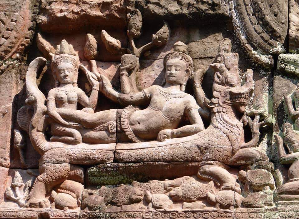 Carving on pediment of Preah Khan Temple showcasing Vishnu god reclining on Naga with his consort doing massage, and intricate carvings in Angkor, Cambodia.
